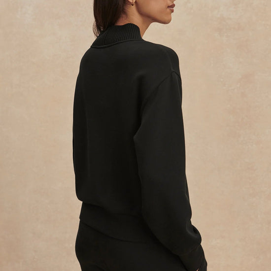 Woman wearing a black turtleneck sweater against a beige background