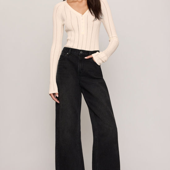 Women’s cream pointelle-knit V-neck henley sweater styled with black wide-leg jeans, available at Ekam boutique Newport Beach
