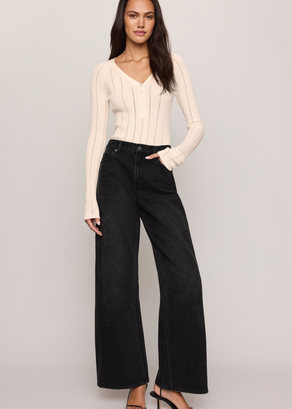 Women’s cream pointelle-knit V-neck henley sweater styled with black wide-leg jeans, available at Ekam boutique Newport Beach