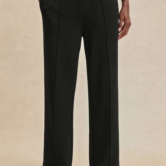 Person wearing black wide-leg pants on a beige background