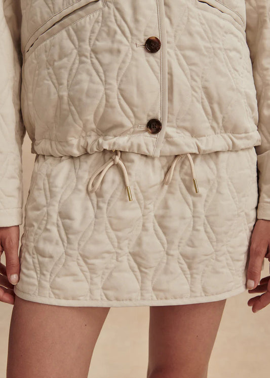 Beige quilted jacket with buttons and drawstring on a beige background