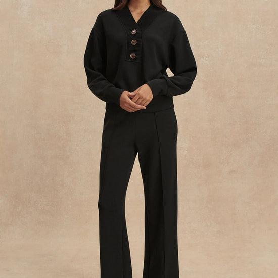 Woman wearing a black outfit with a beige background