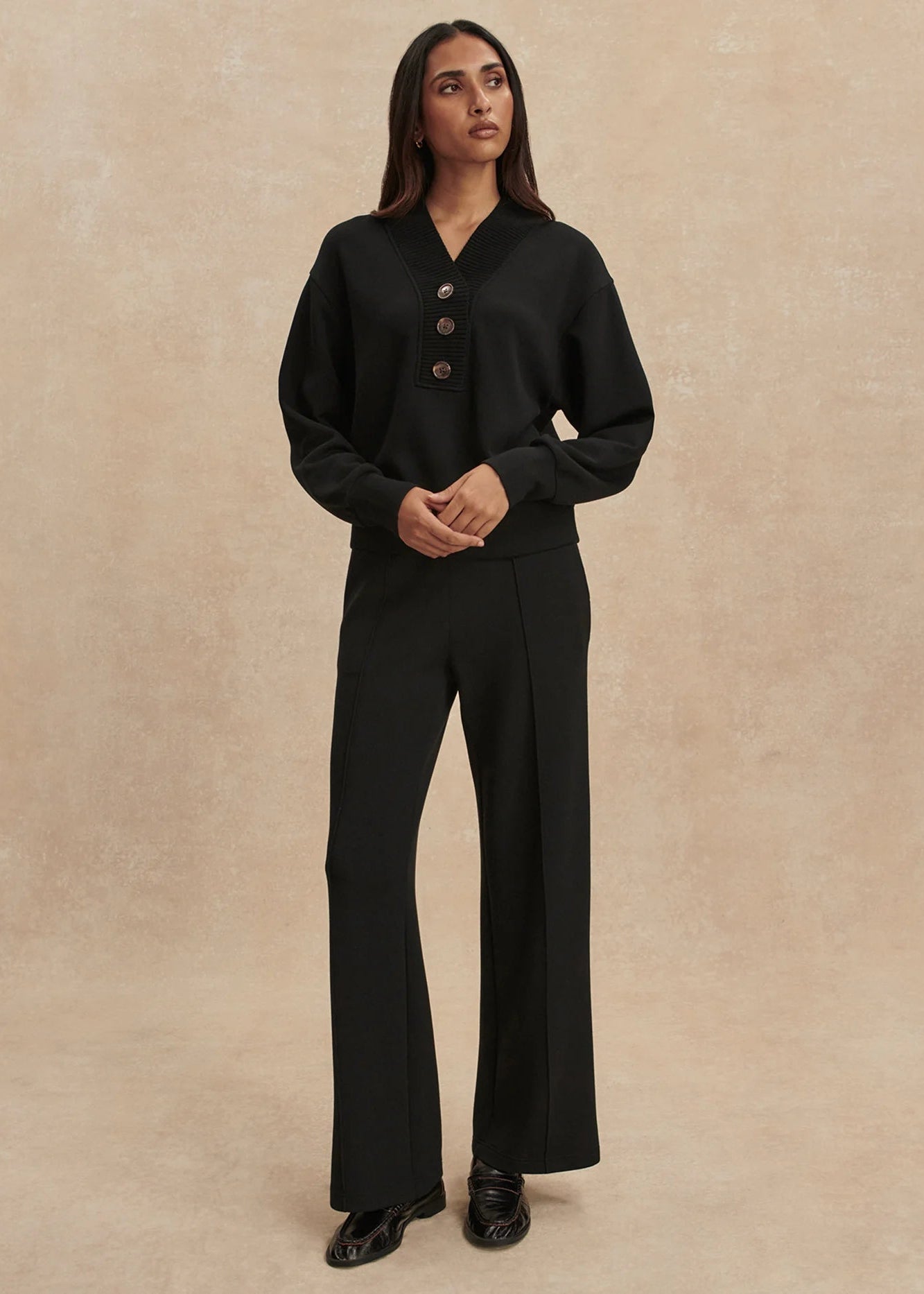 Woman wearing a black outfit with a beige background