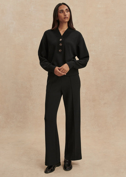 Woman wearing a black outfit with a beige background