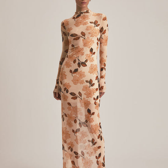 Woman wearing a floral patterned dress on a plain background