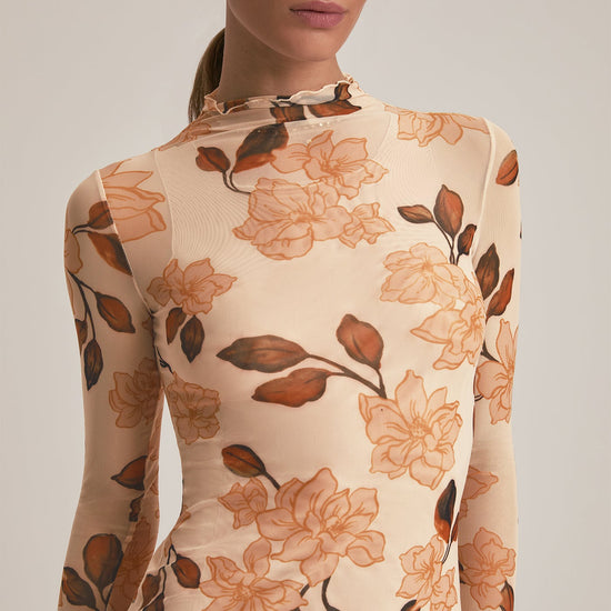 Woman wearing a floral-patterned dress with long sleeves on a plain background