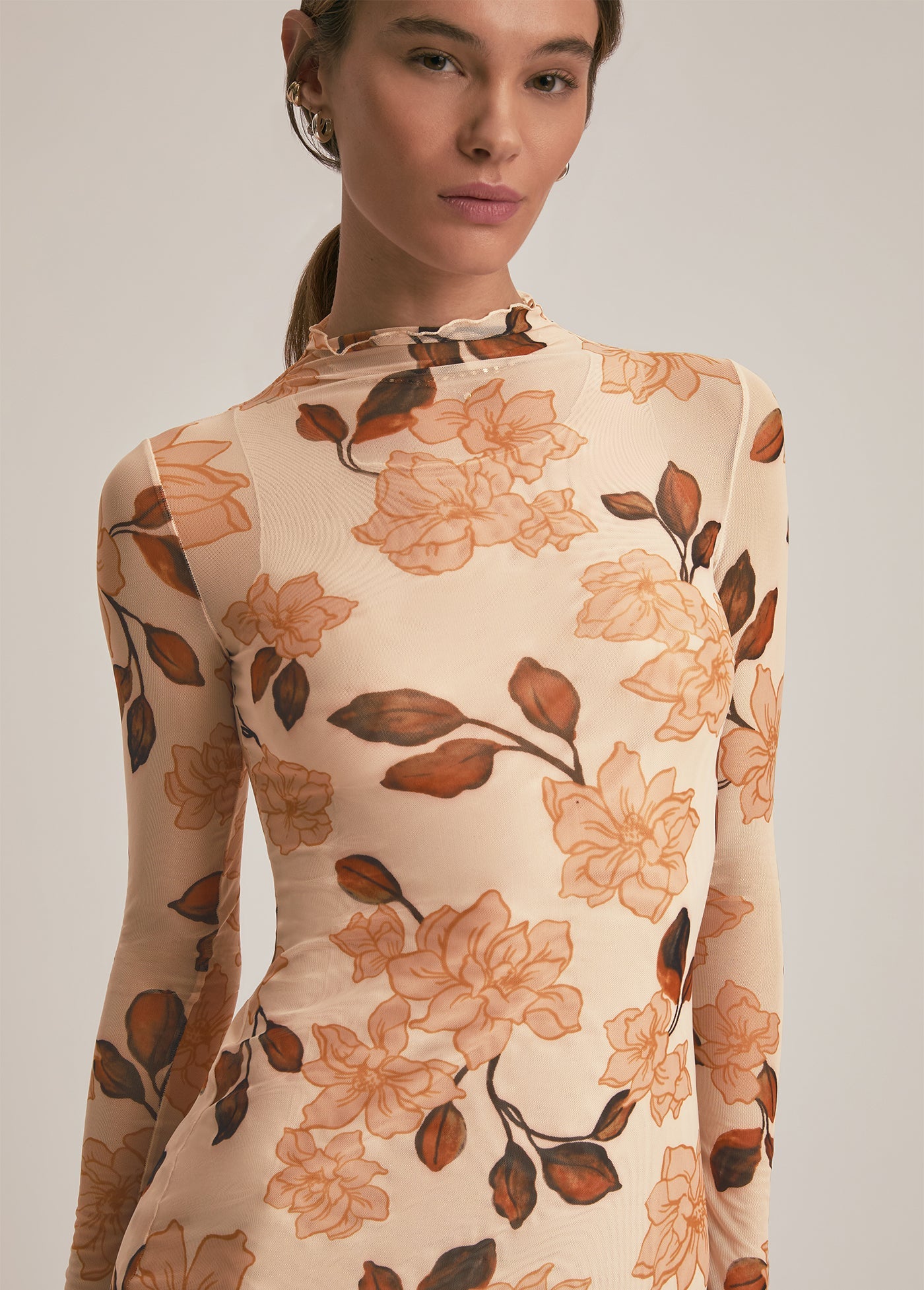 Woman wearing a floral-patterned dress with long sleeves on a plain background