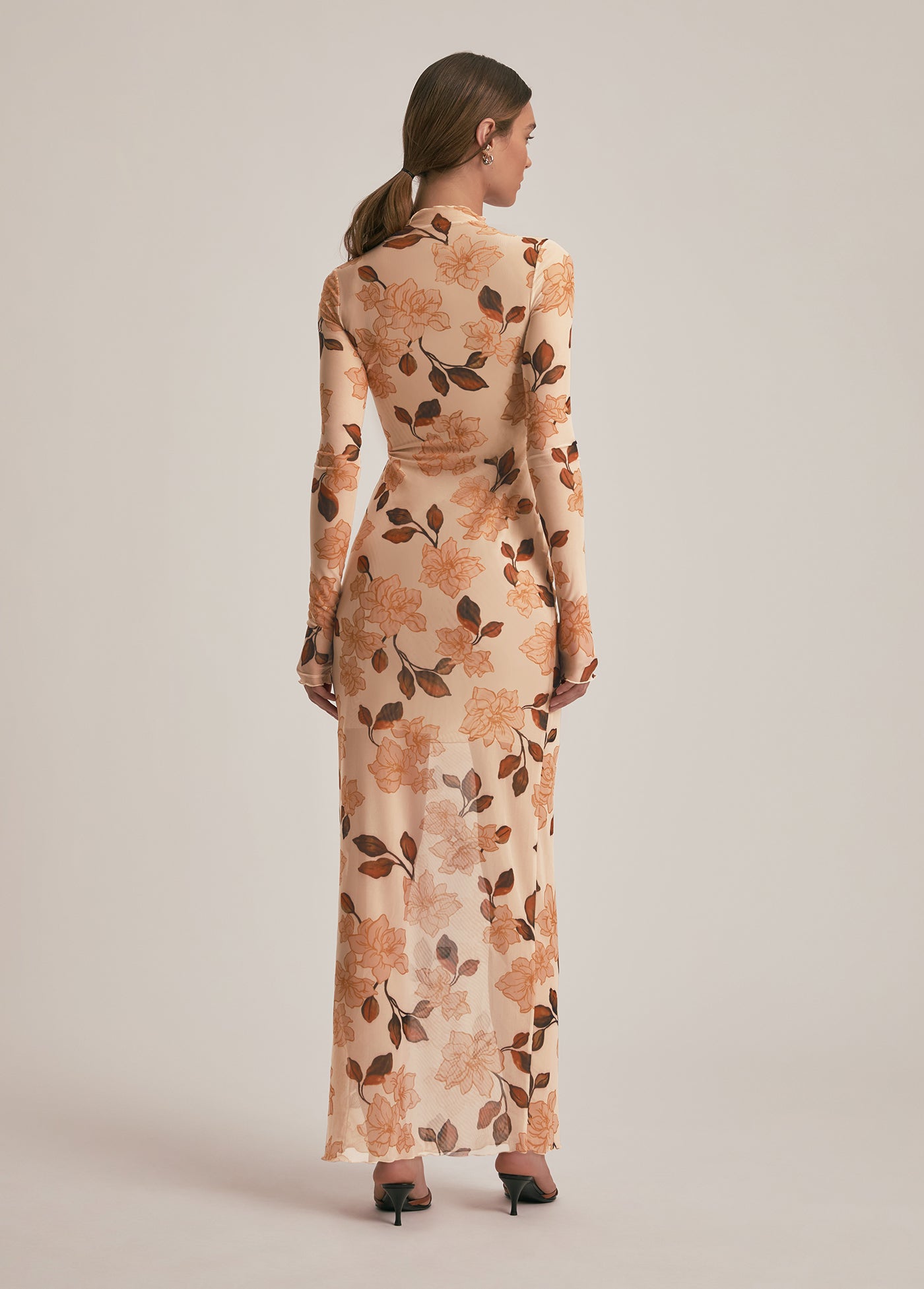 Woman wearing a floral dress with long sleeves on a plain background
