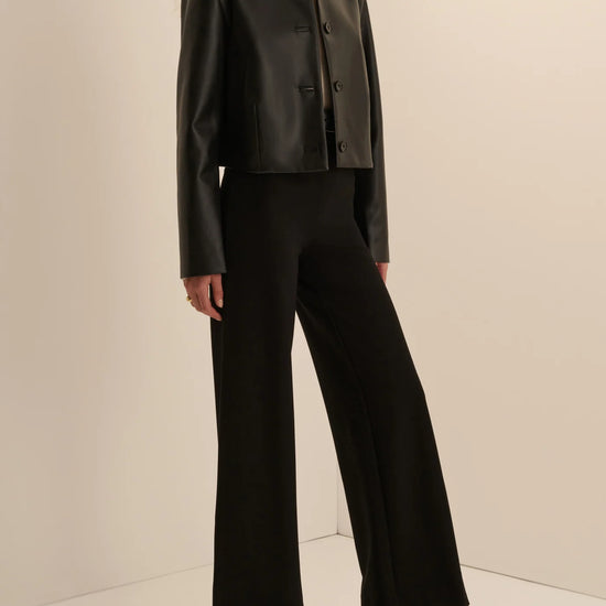 Women’s black leather cropped button-front jacket and midi pencil skirt with front slit, available at Ekam boutique Newport Beach
