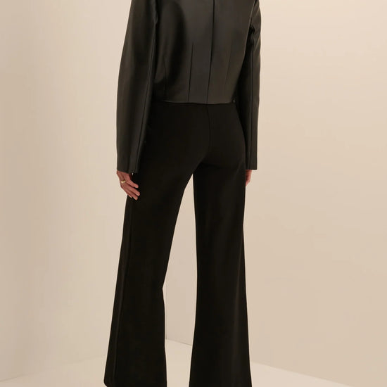 Women’s black leather cropped button-front jacket and midi pencil skirt with front slit, available at Ekam boutique Newport Beach