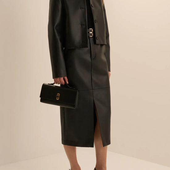 Women’s black leather cropped button-front jacket and midi pencil skirt with front slit, available at Ekam boutique Newport Beach