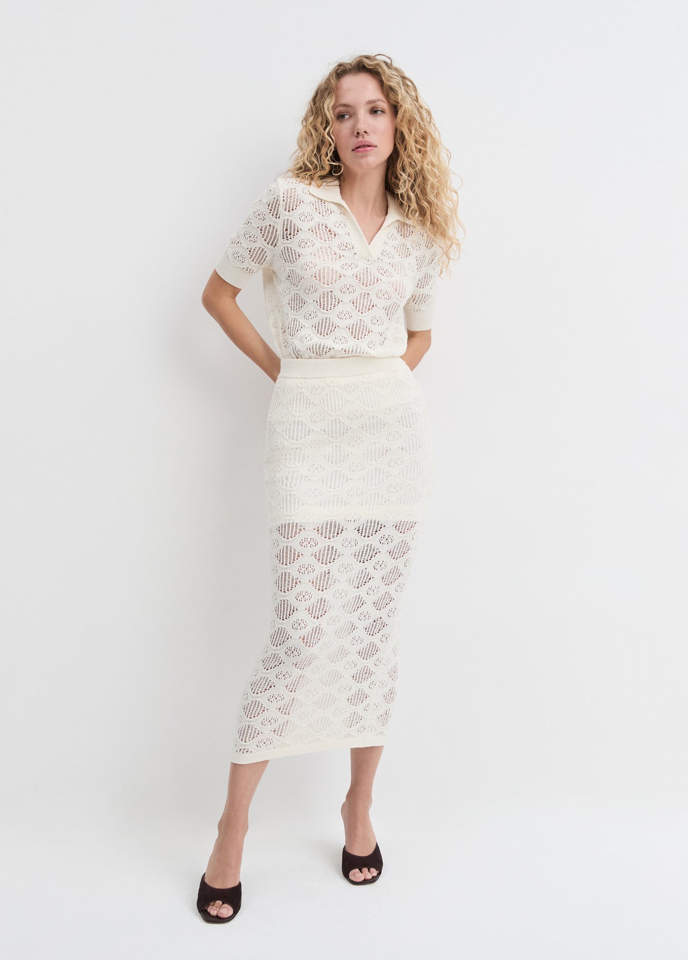 Woman wearing a white lace outfit on a plain background