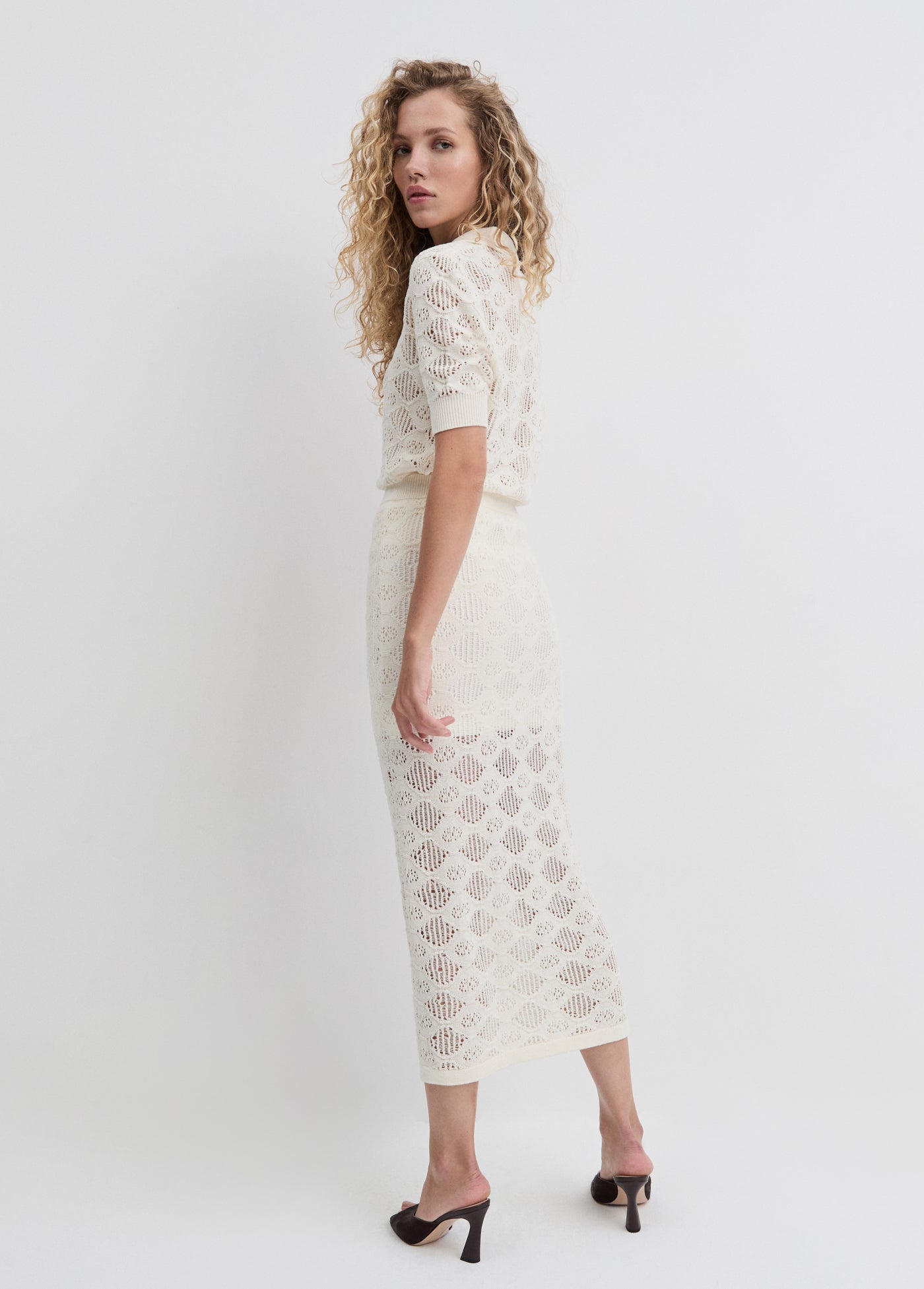 Woman wearing a white lace dress on a plain background