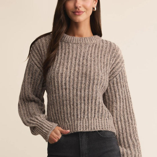 Woman wearing a brown knitted sweater against a beige background