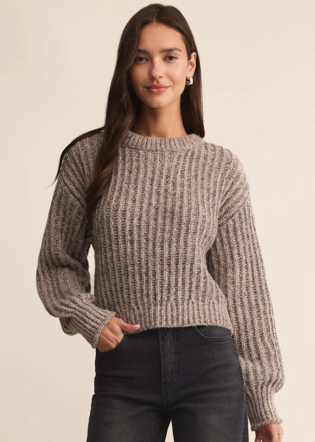 Woman wearing a brown knitted sweater against a beige background