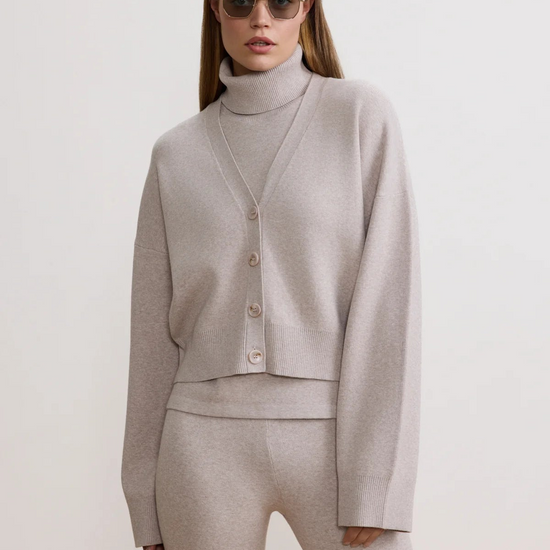 Woman wearing a light gray outfit with a cardigan and pants on a white background